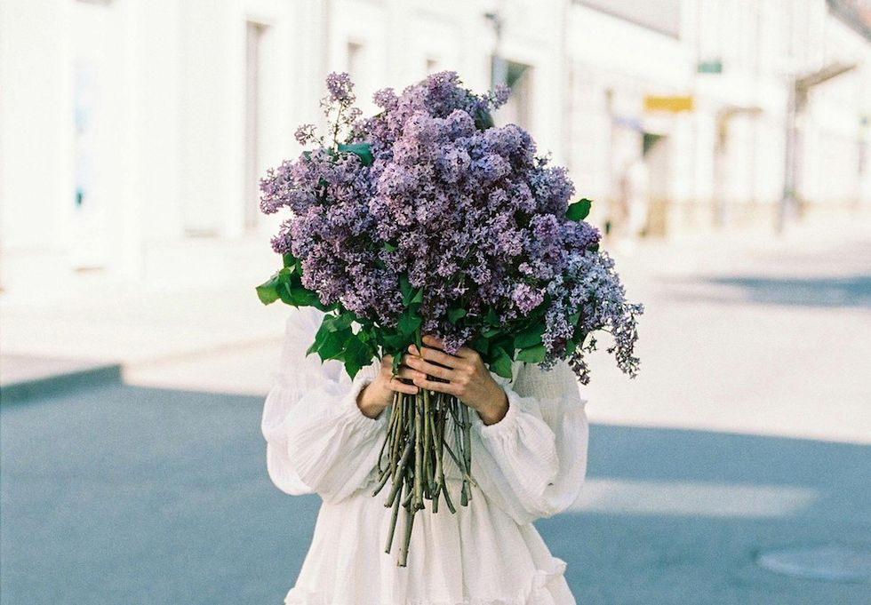 woman holding a big bouquet of purple flowers