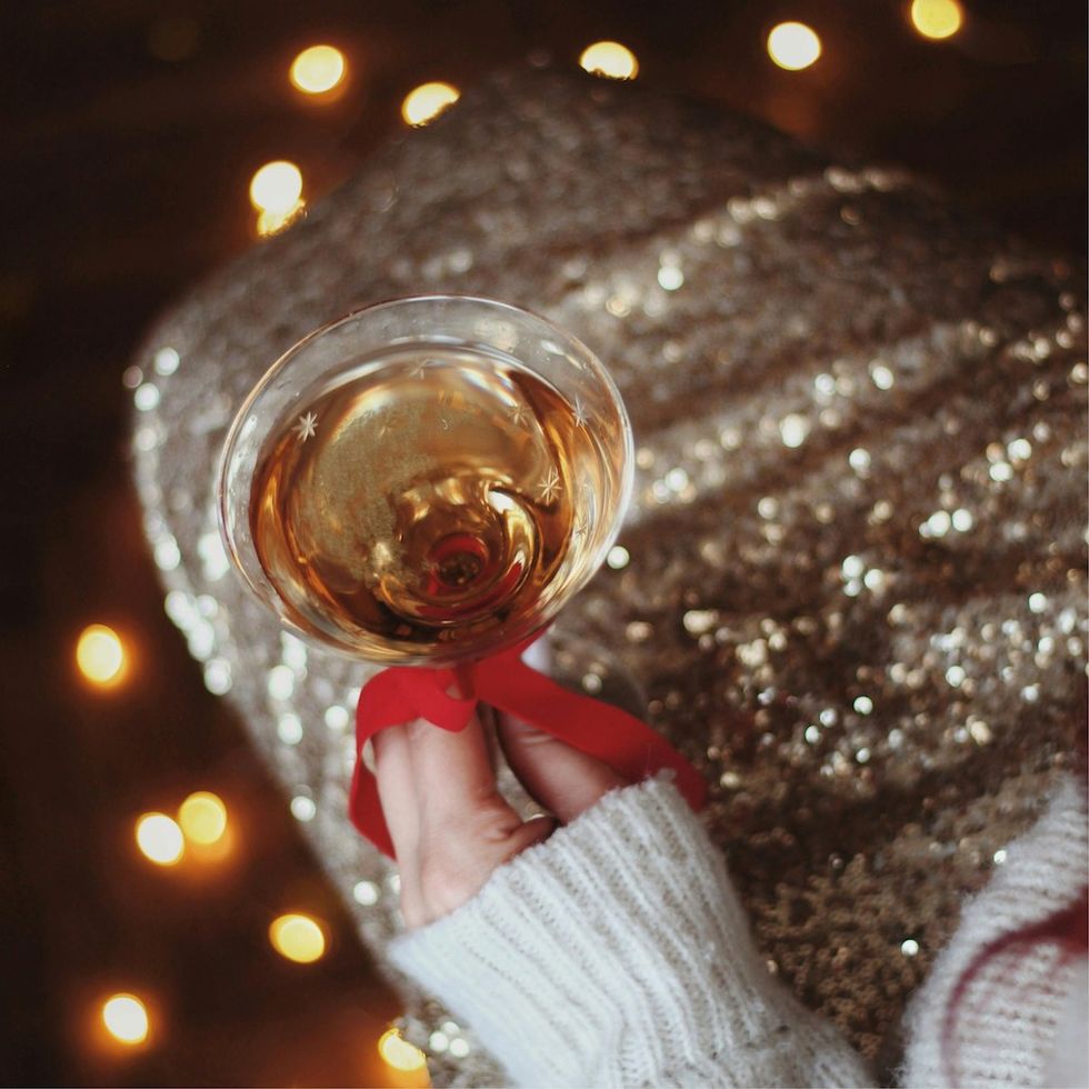 woman holding a coup of champagne with a red ribbon tied on the stem