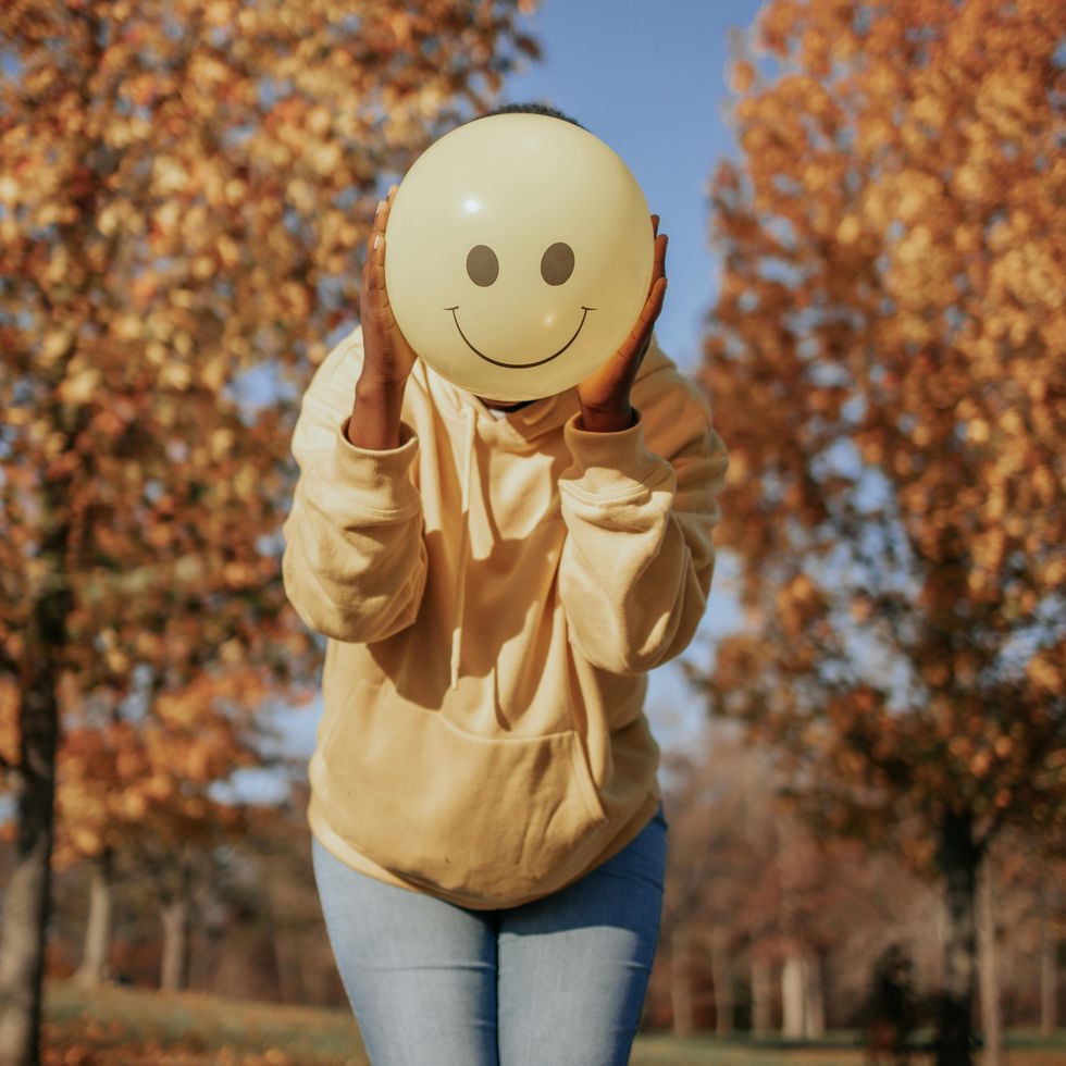 woman holding a smiley face balloon