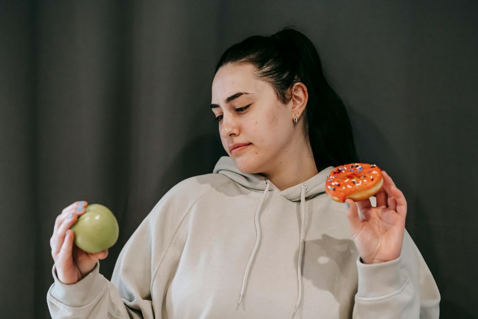woman holding apple and doughnut