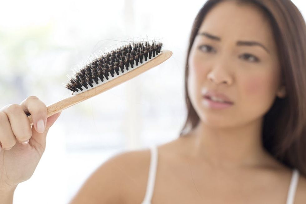 Woman holding hairbrush with worried expression