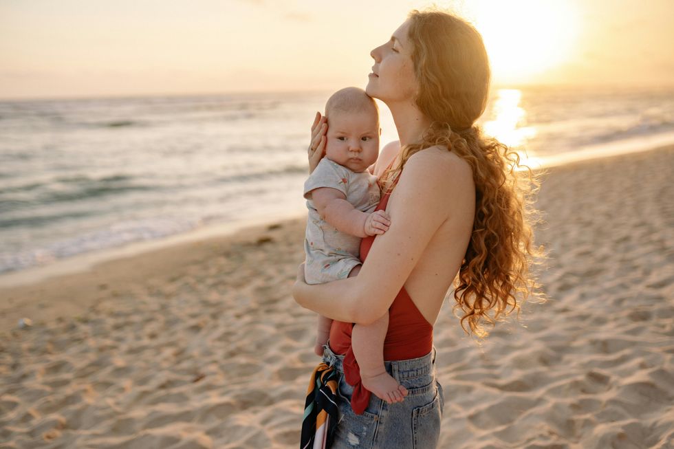 woman holding her baby on the beach