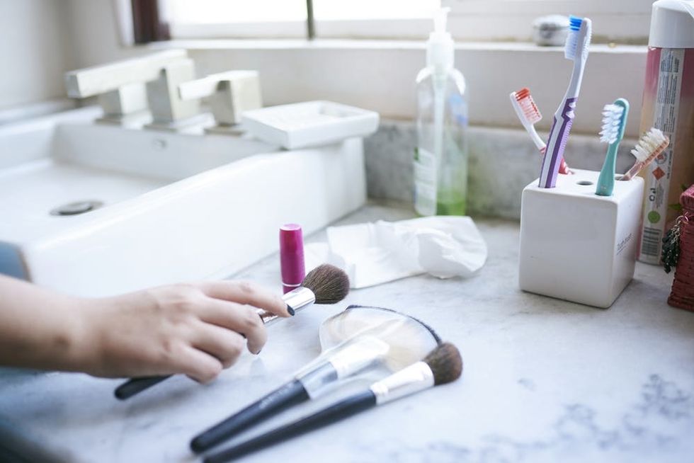 Woman holding makeup brushes between cleaning them. 