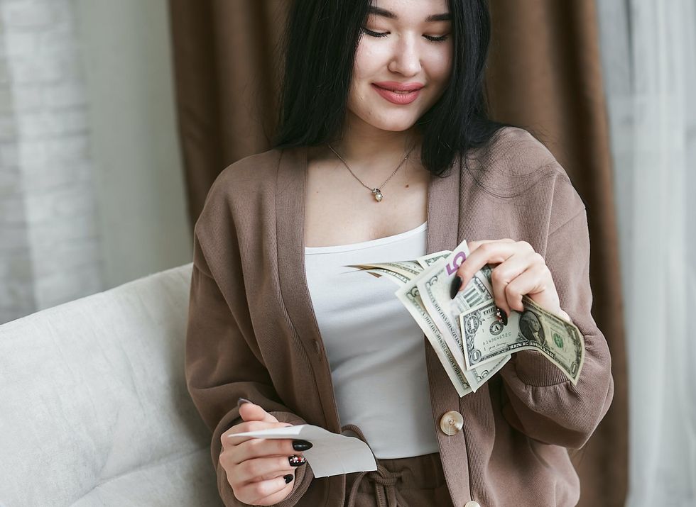 woman holding receipt while looking at cash