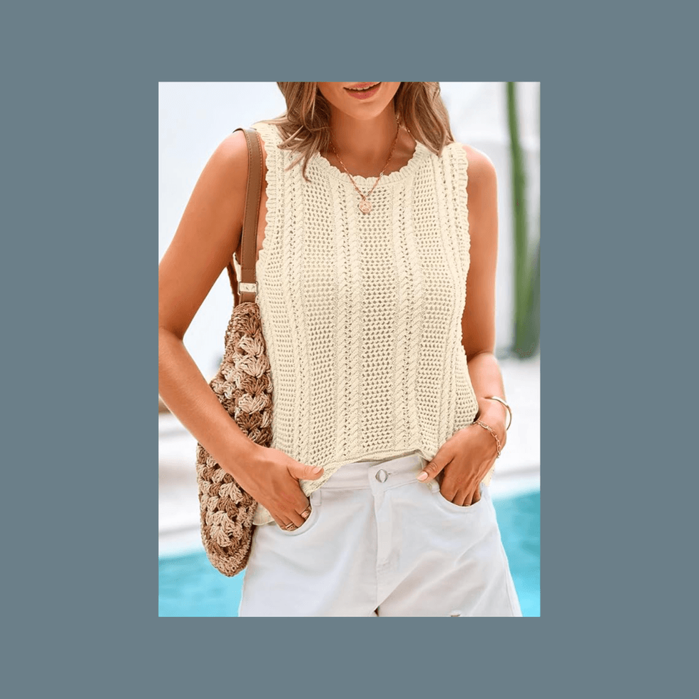 Woman in a beige knit top and white pants, holding a crochet bag.
