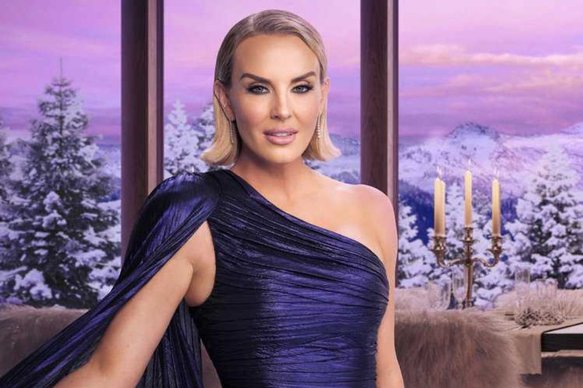 Woman in a blue dress with snowy mountain view and candles in background.