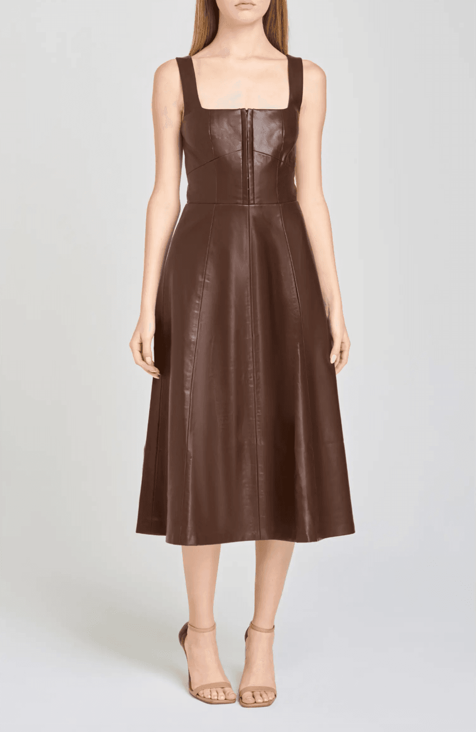 Woman in a brown leather midi dress with wide straps and front zip closure.
