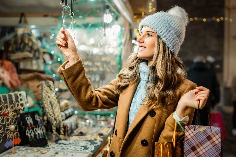 Woman in a coat and beanie shopping for jewelry at an outdoor market.