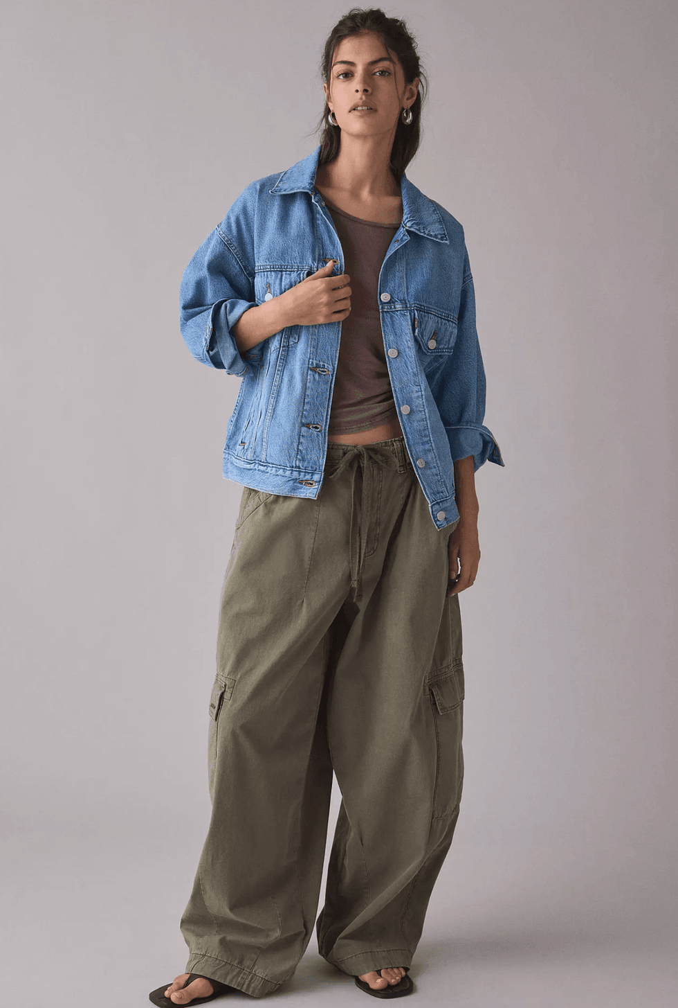 Woman in a denim jacket with cargo pants and black sandals.