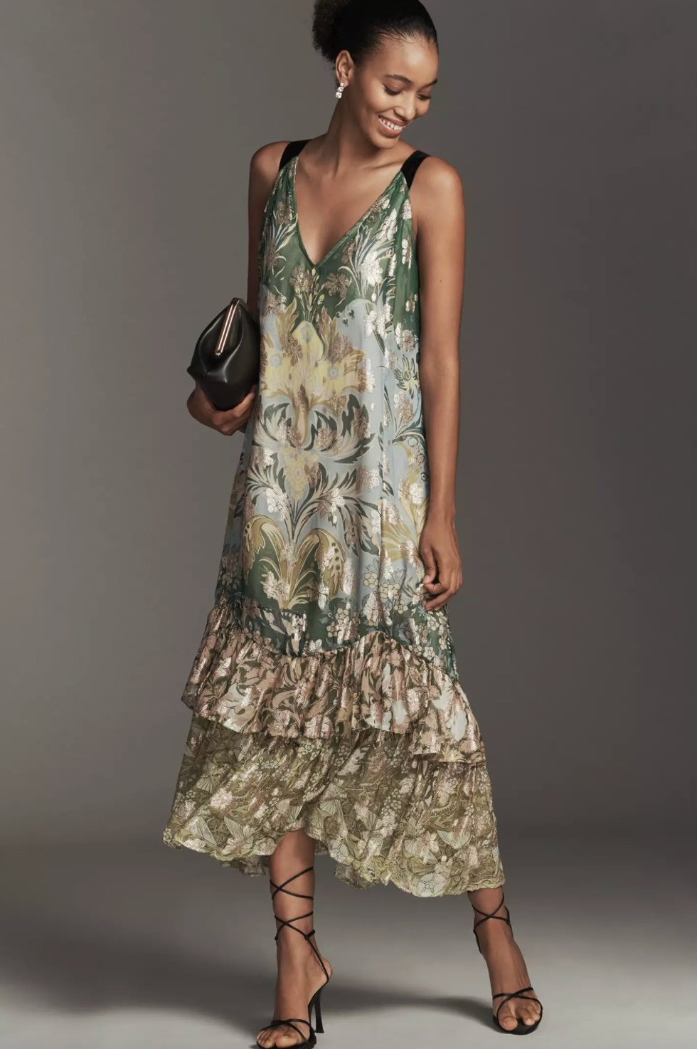 Woman in a floral tiered dress, holding a clutch, wearing strappy heels.