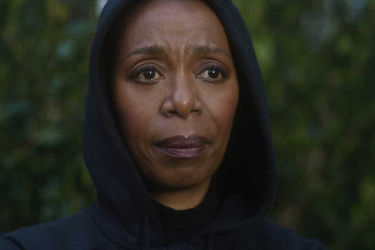 woman in a hoodie standing outside surrounded by greenery