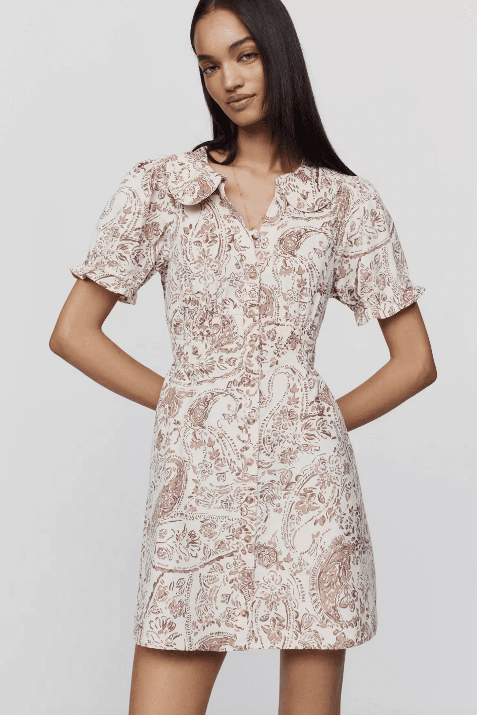 Woman in a patterned white and brown button-up dress with short sleeves.