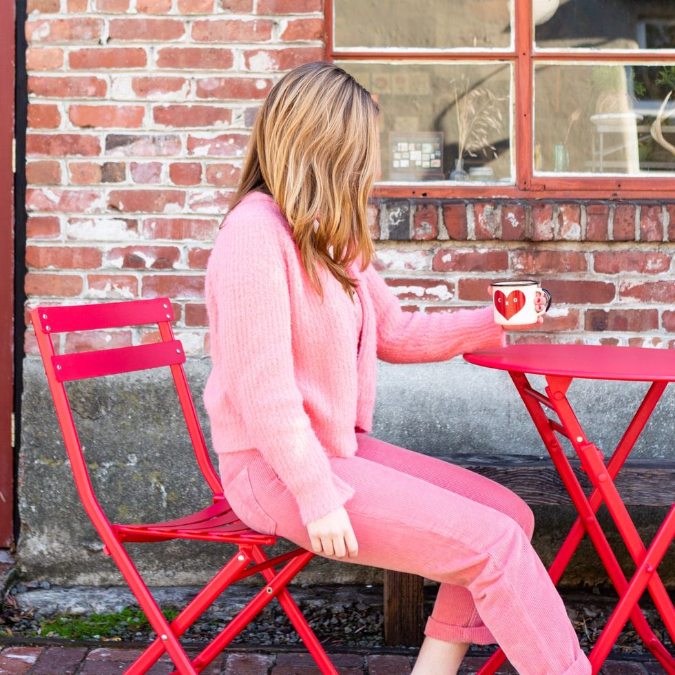 woman in a pink outfit sitting at a red table