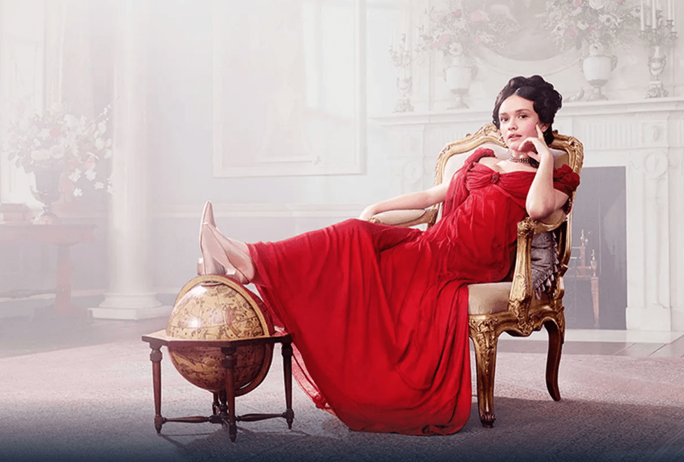 Woman in a red gown lounging with feet on a globe in an elegant room.