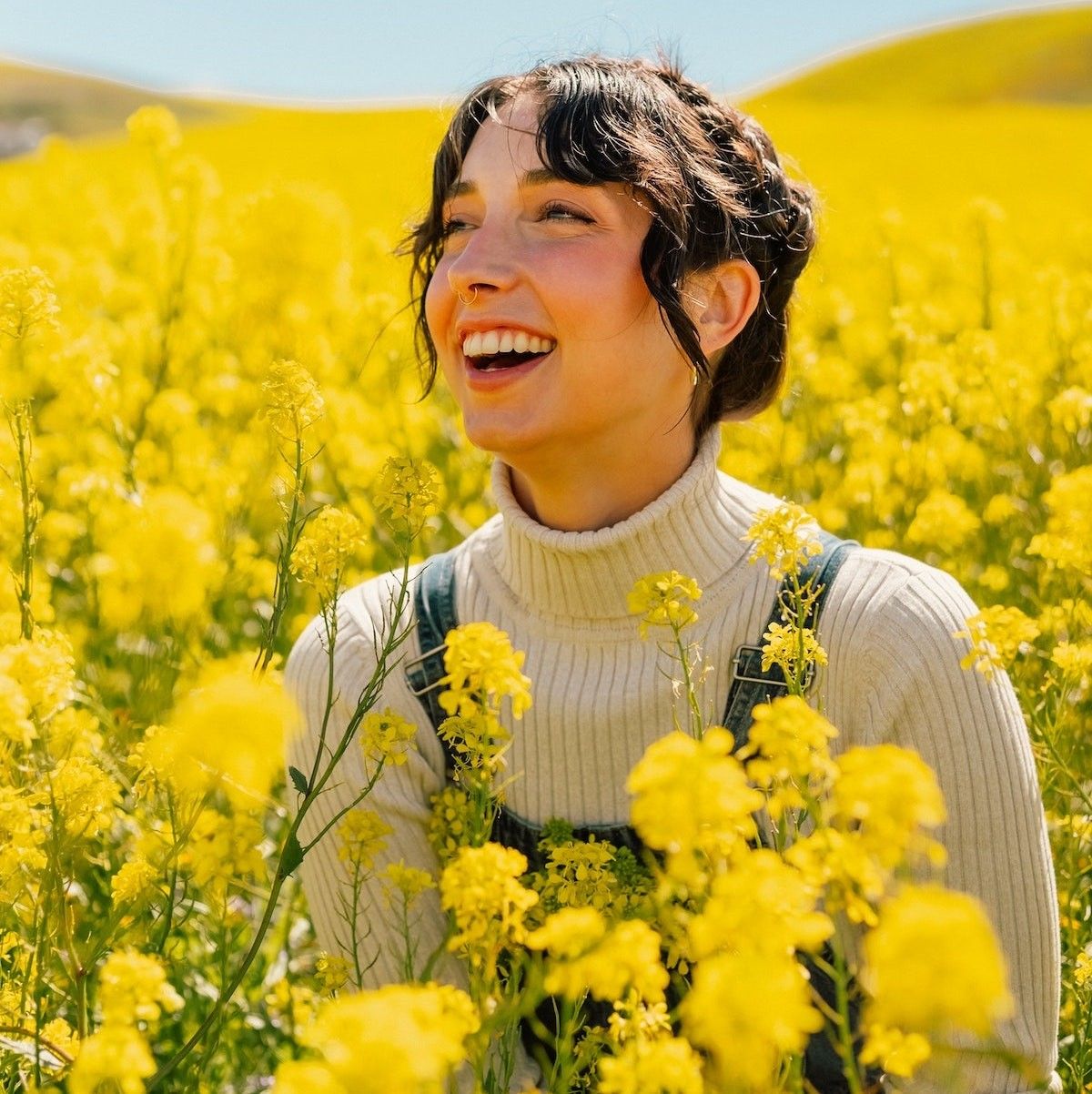 woman in a turtleneck sitting in a field of flowers how to flirt with confidence
