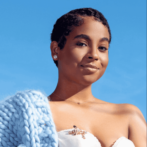 Woman in a white dress and blue shawl under a clear blue sky.