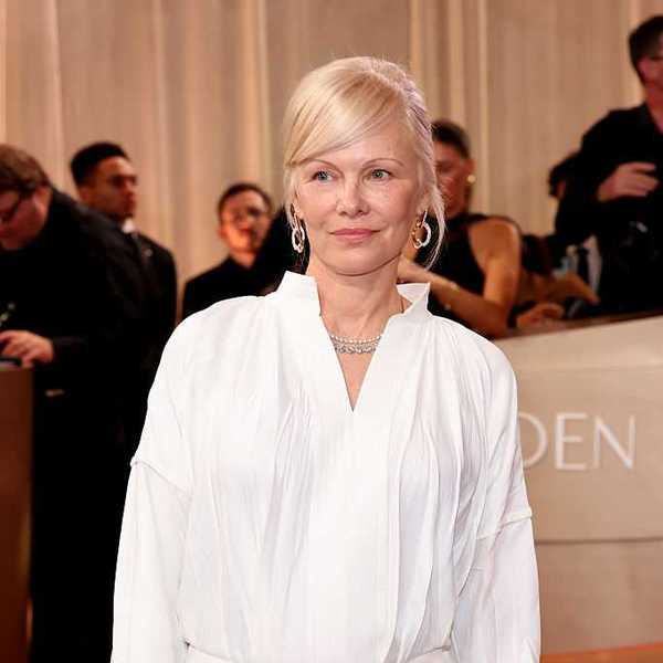 Woman in a white dress poses on a red carpet at an event.