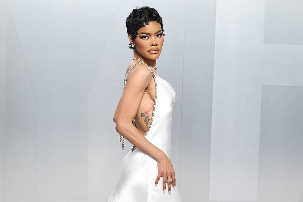 Woman in a white dress with a chic hairstyle posing confidently.