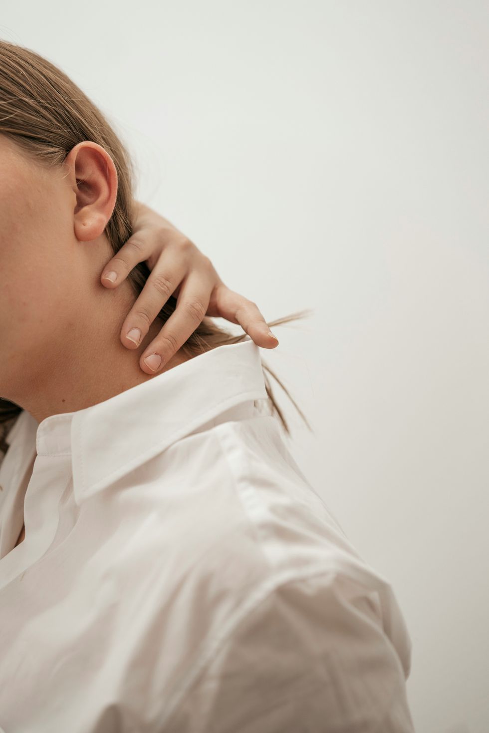 woman in a white shirt rubbing her neck