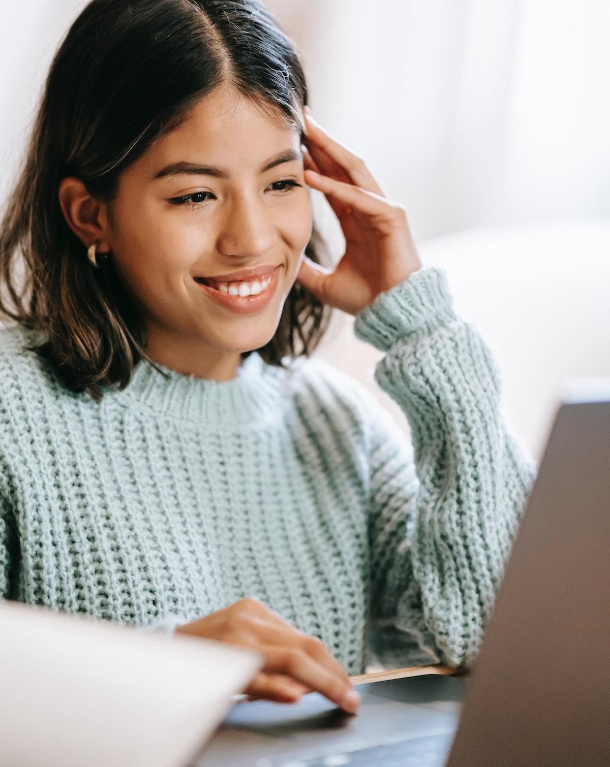woman in an aqua sweater typing on her computer NaNoWriMo