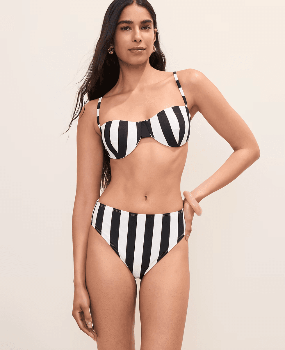 Woman in black and white striped bikini, standing against a neutral background.
