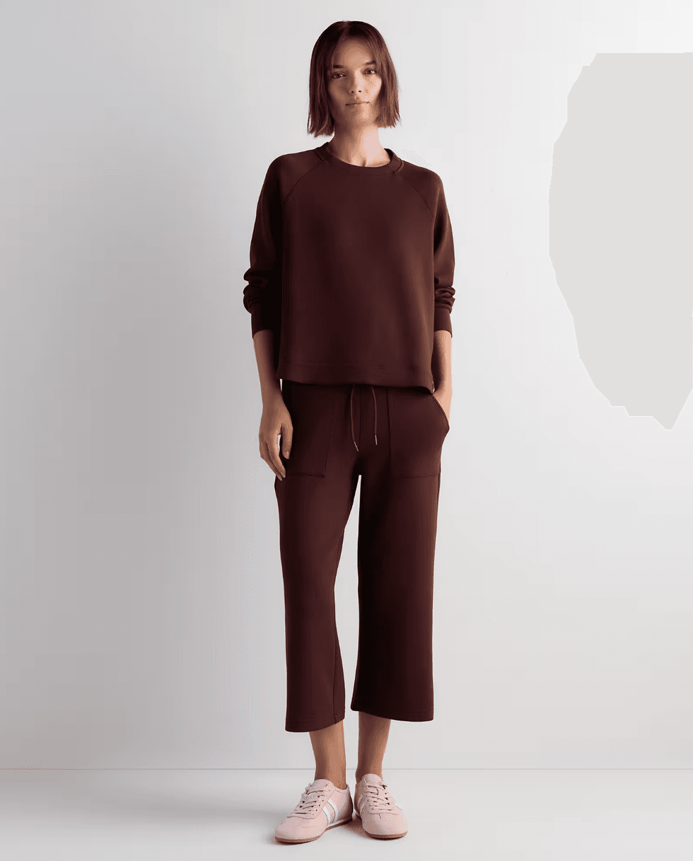 Woman in brown loungewear set with pink sneakers, standing against a plain white background.