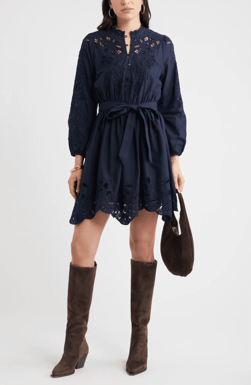 Woman in navy dress with lace details, brown boots, and matching handbag.