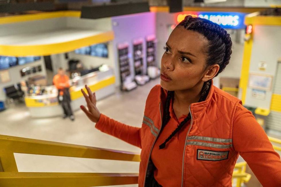 Woman in orange vest looking concerned inside a modern, colorful workspace.