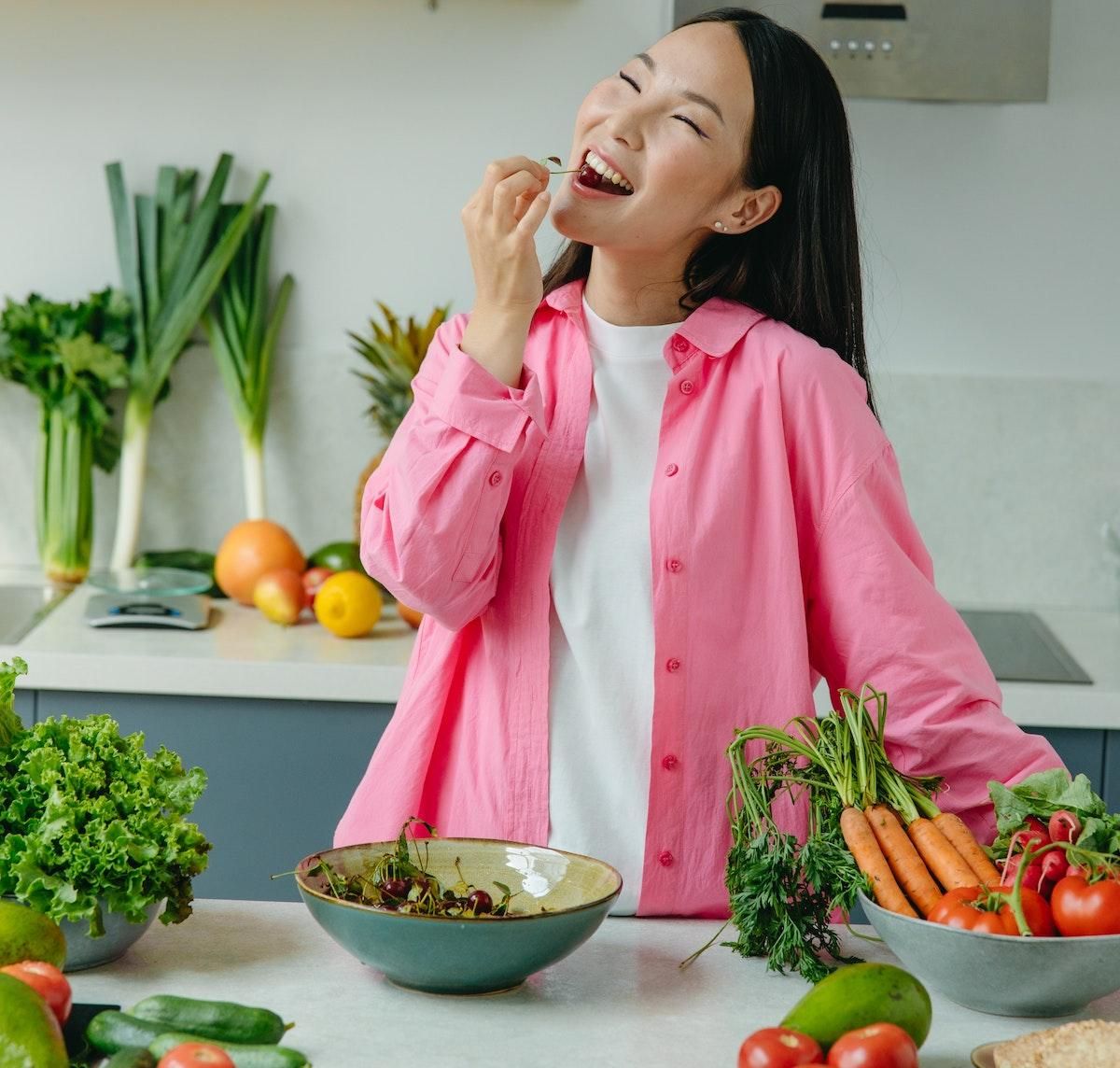 woman in pink shirt eating fruit and veggies
