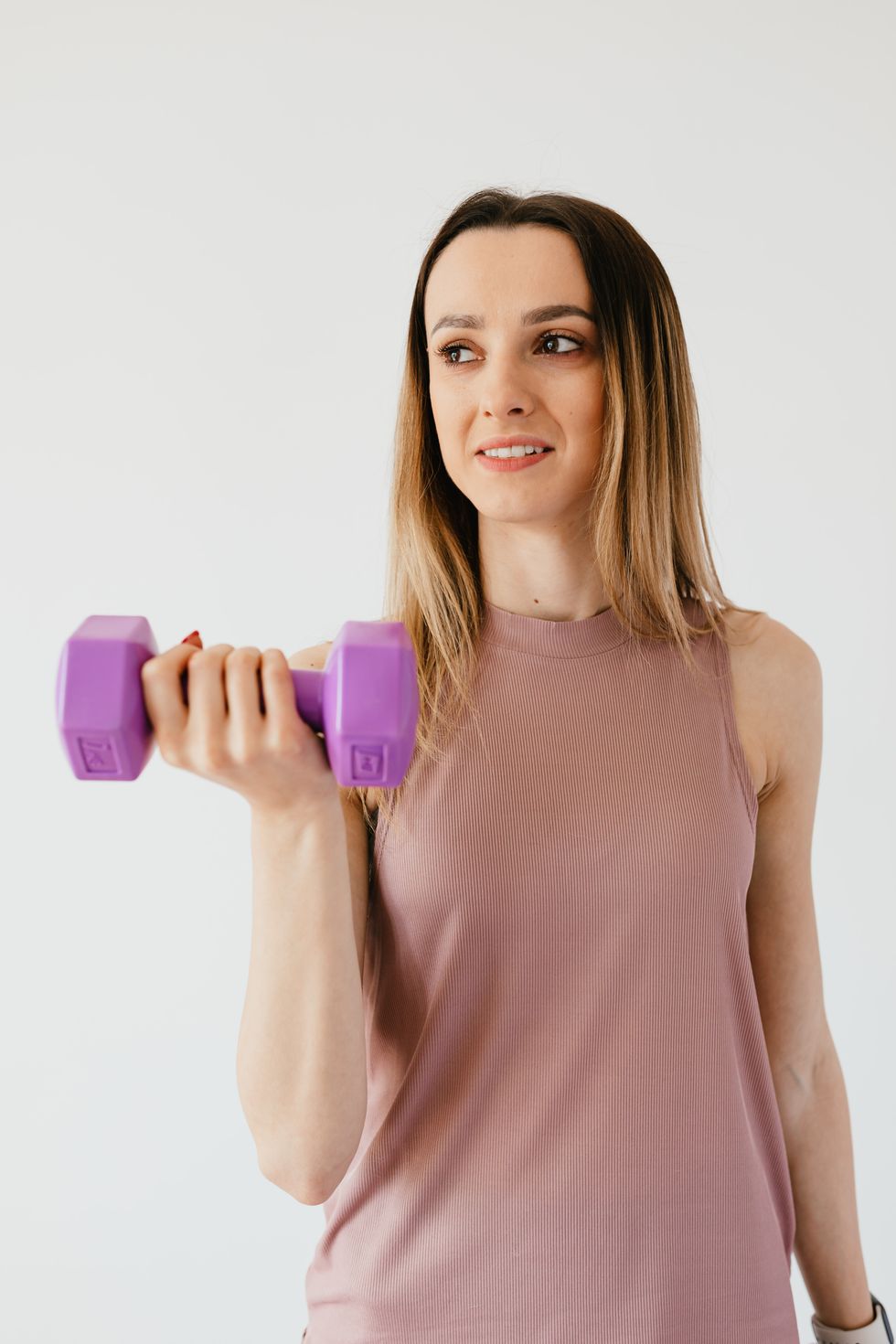 woman in pink tank top lifting weights for strength training