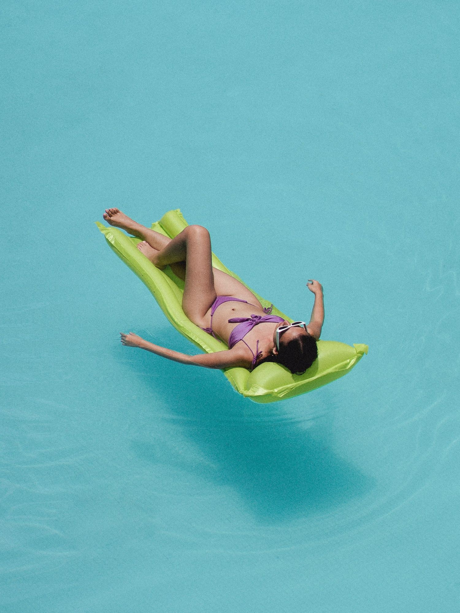 woman in purple bikini floating on a raft in a pool