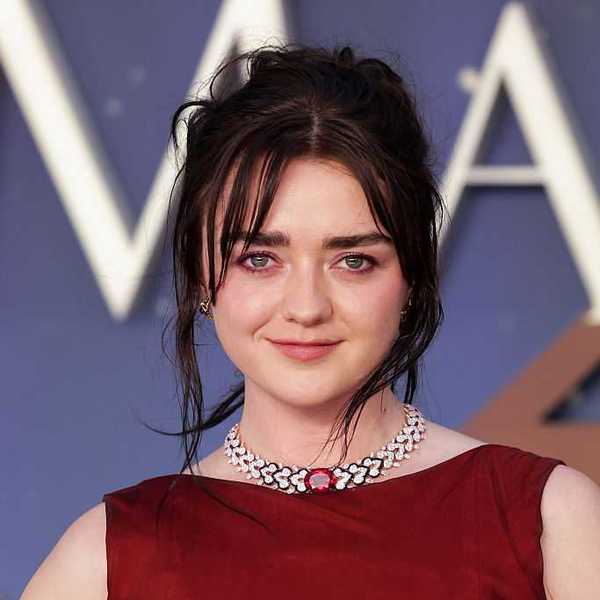 Woman in red dress with necklace, smiling at an event.