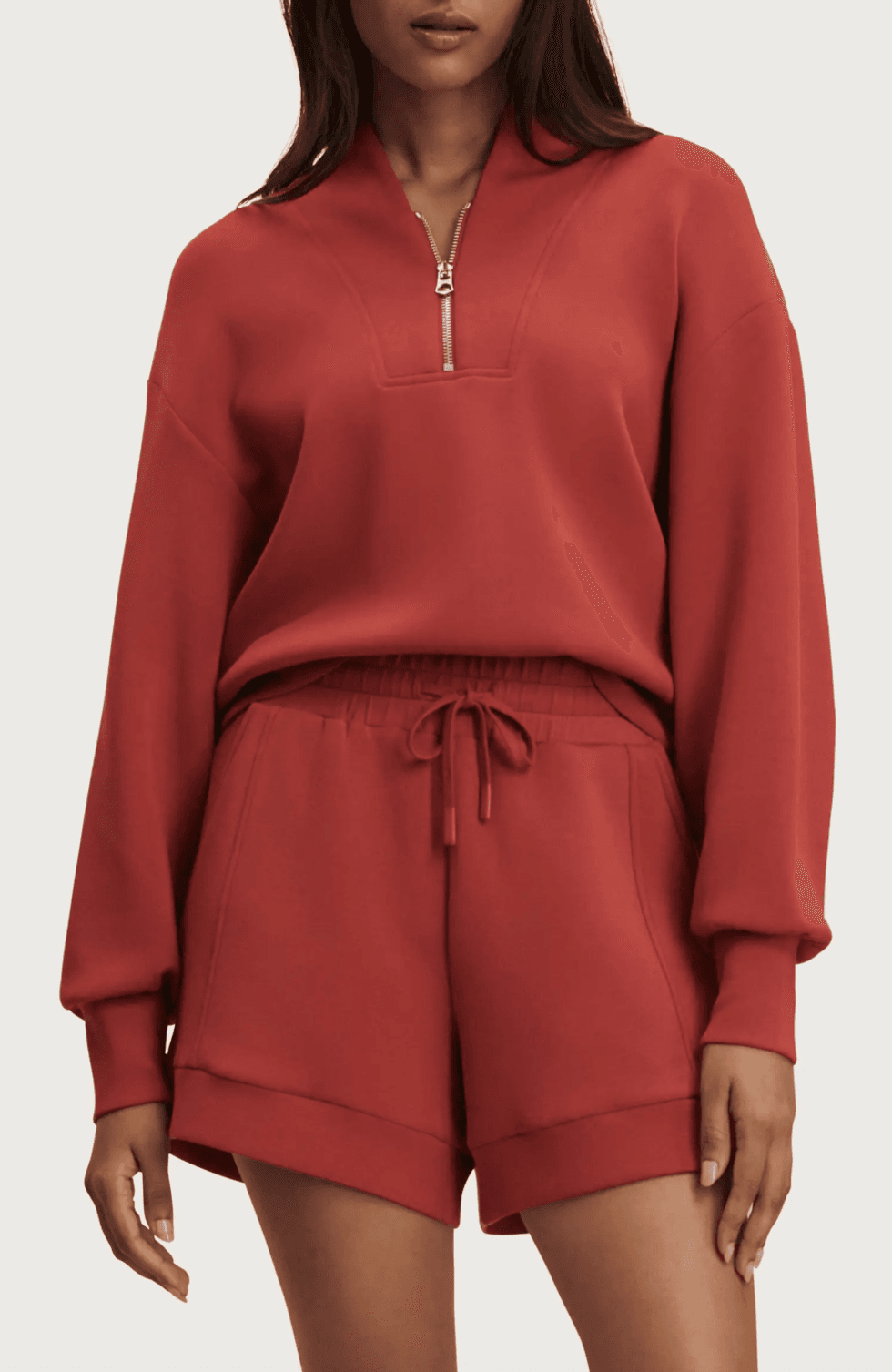 Woman in red half-zip sweatshirt and matching shorts.