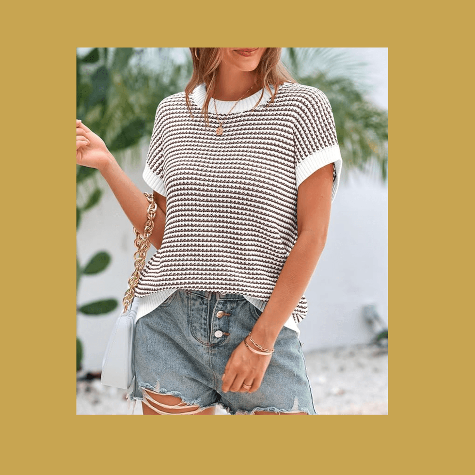 Woman in striped top and denim shorts with shoulder bag.