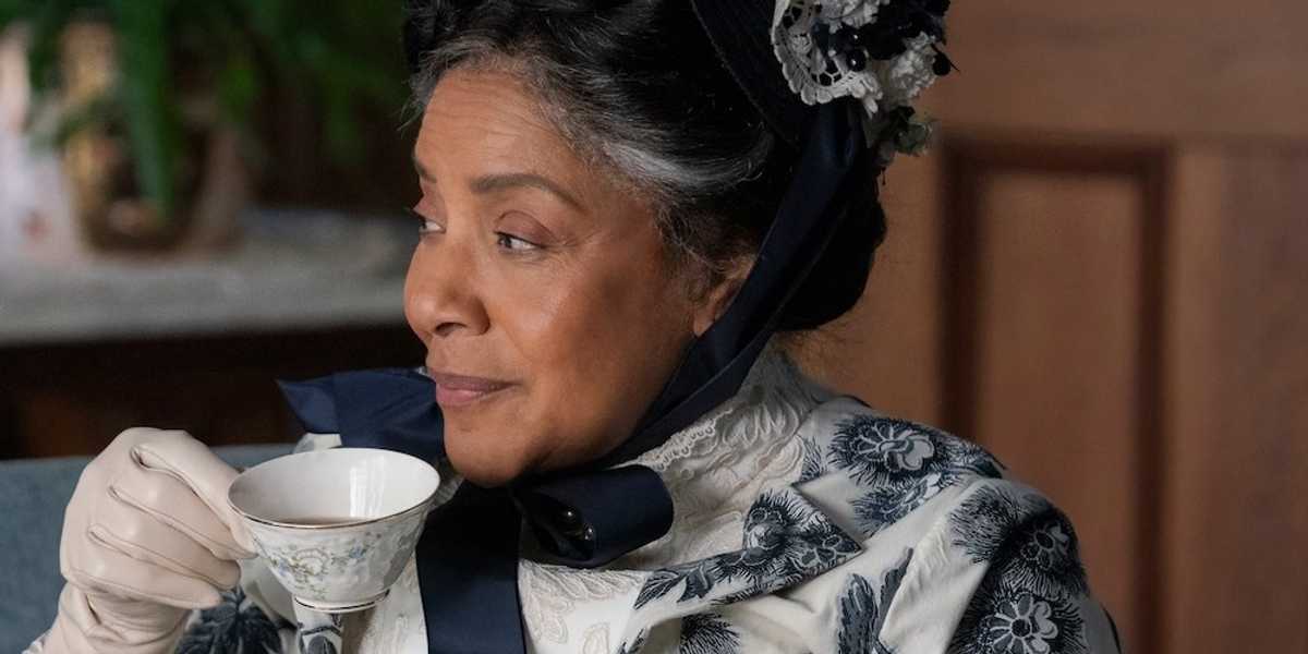 Woman in vintage clothing sipping tea, wearing a floral hat and gloves.