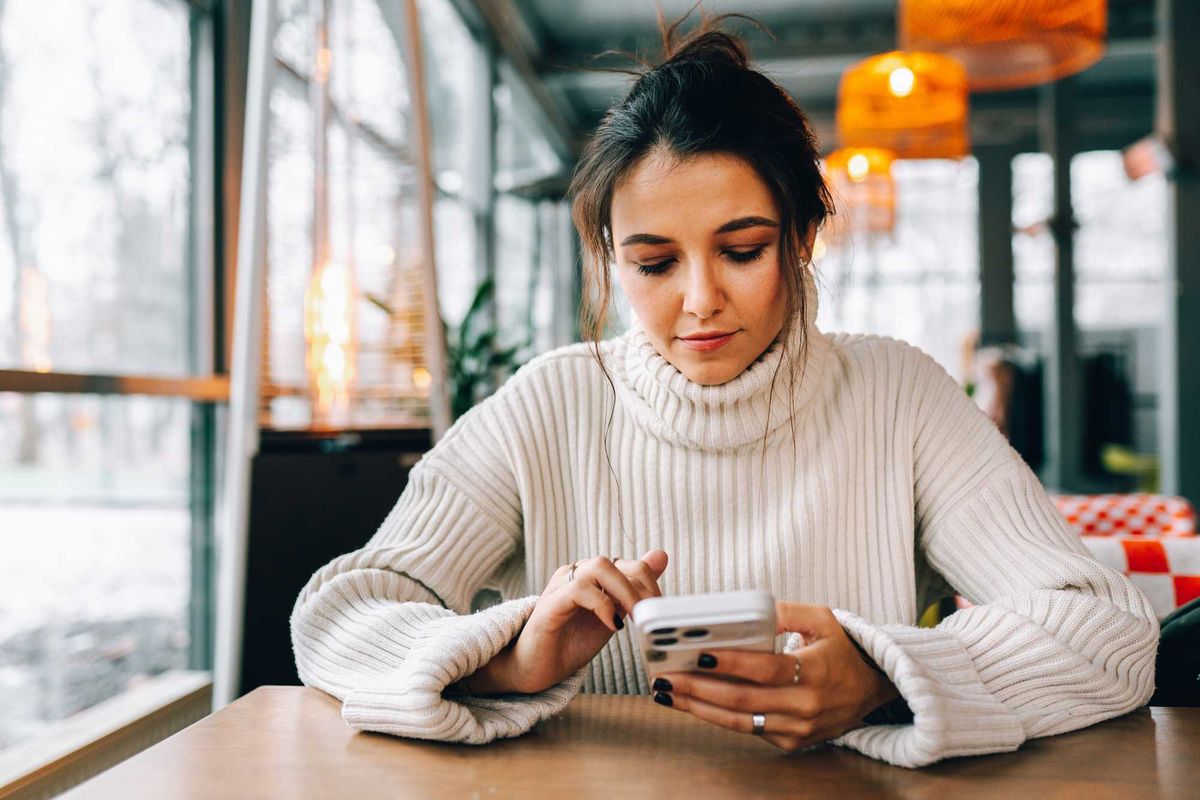 woman in white sweater on phone