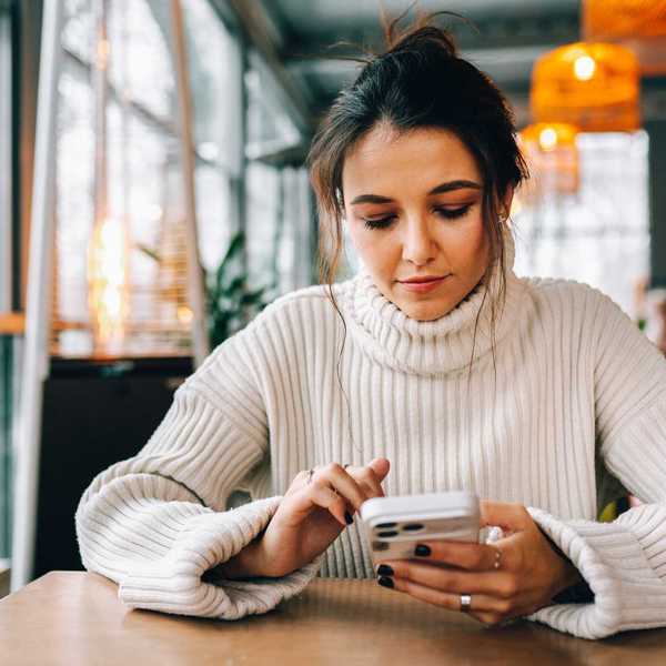 woman in white sweater on phone