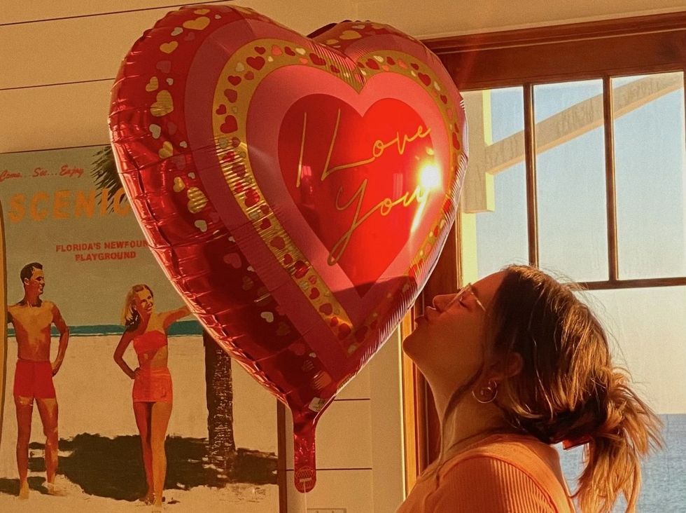 woman kissing heart-shaped valentine's day 'i love you' balloon