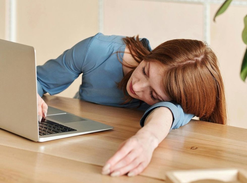 woman laying on her desk next to her laptop