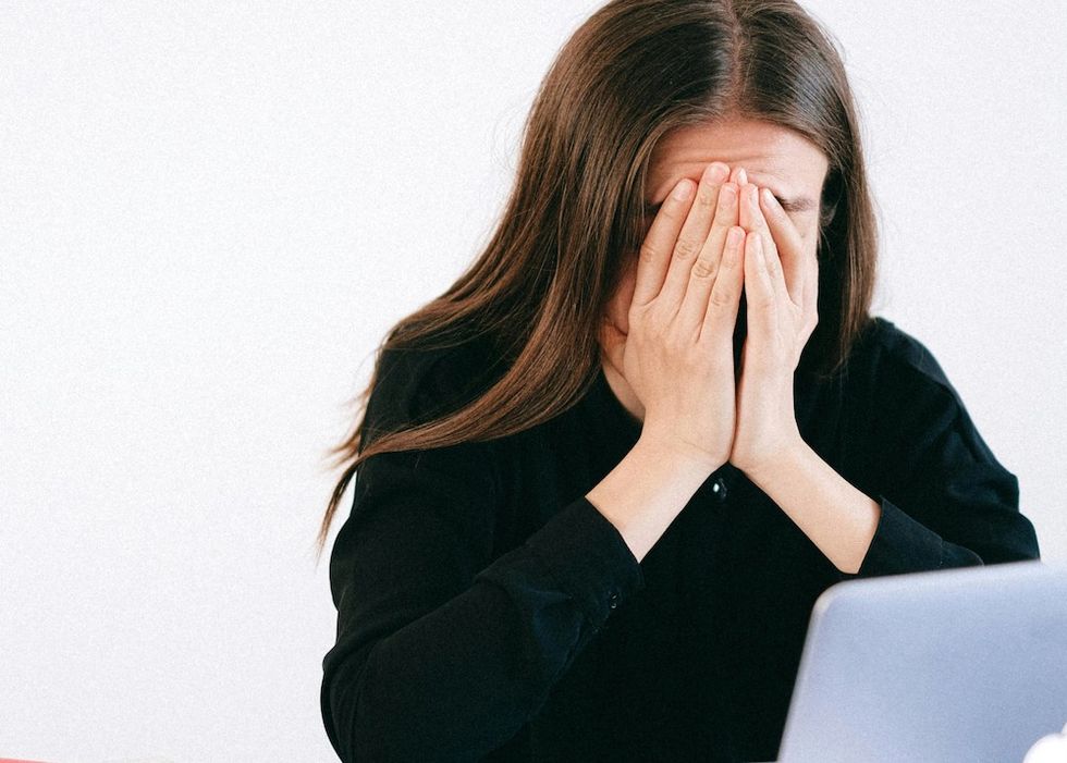 woman looking at her laptop with her face in her hands