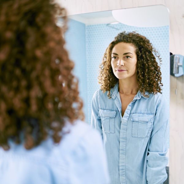 woman looking at her reflection blue shirt