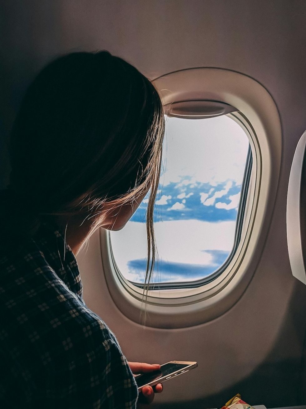 woman looking out a plane window