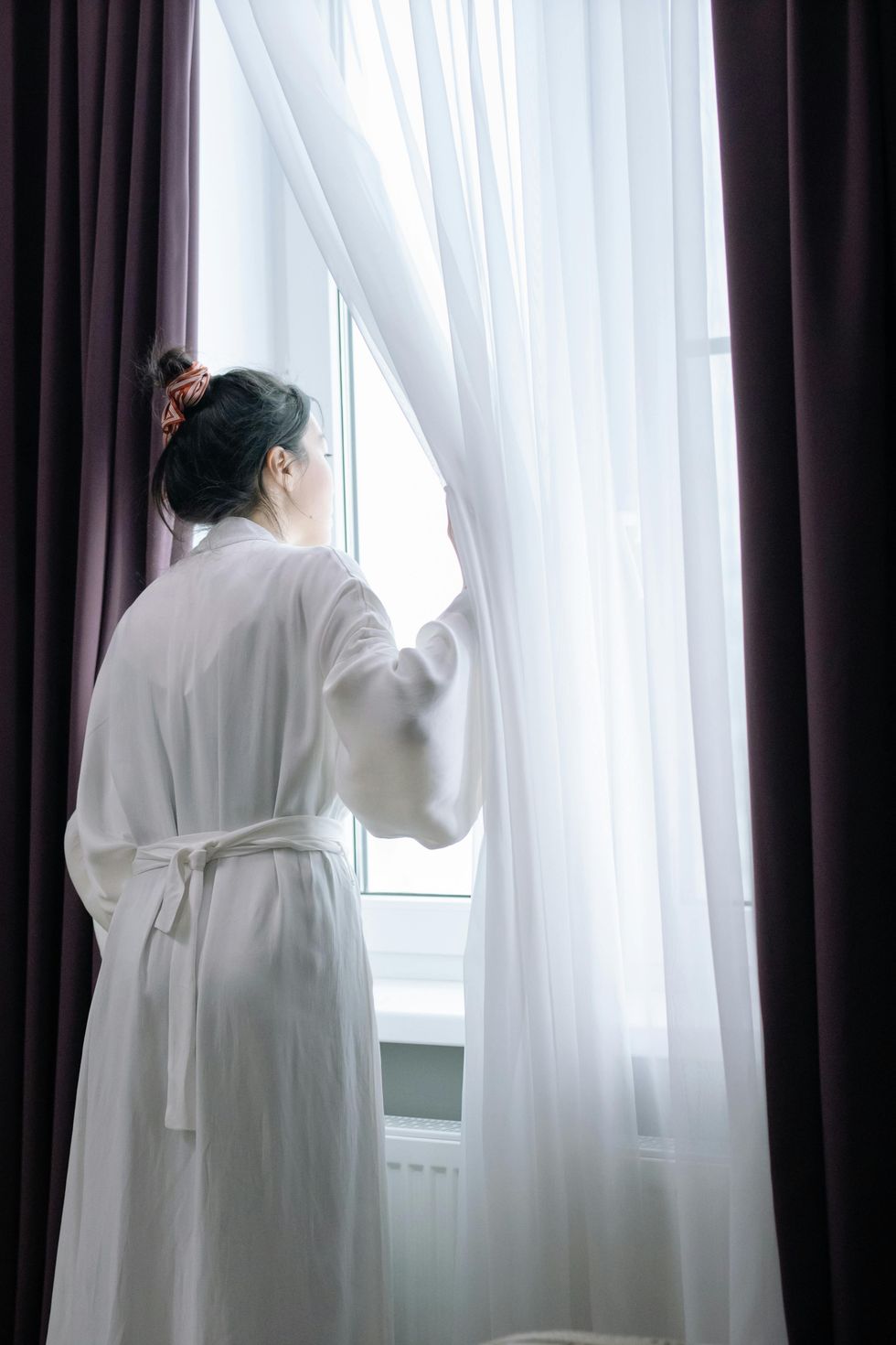woman looking out blinds