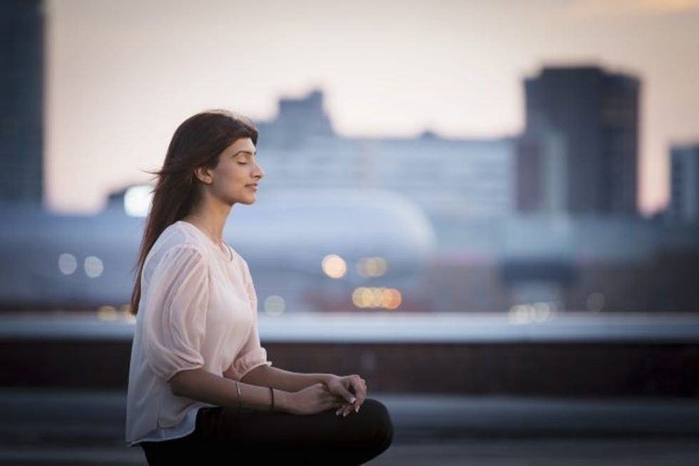 Woman meditating on rooftop