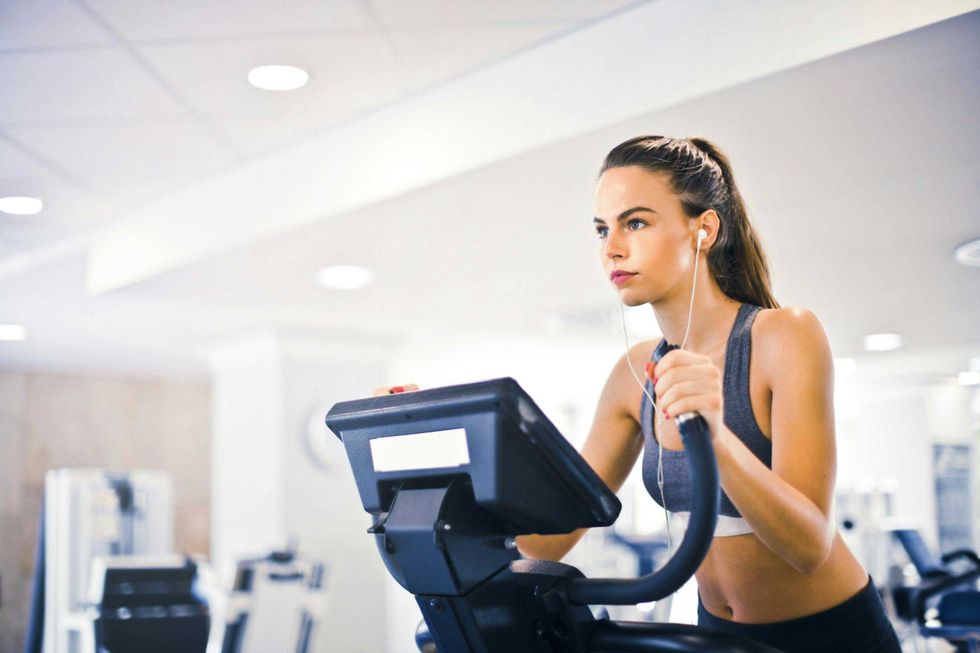 Woman on exercise bike wearing earphones in a gym.