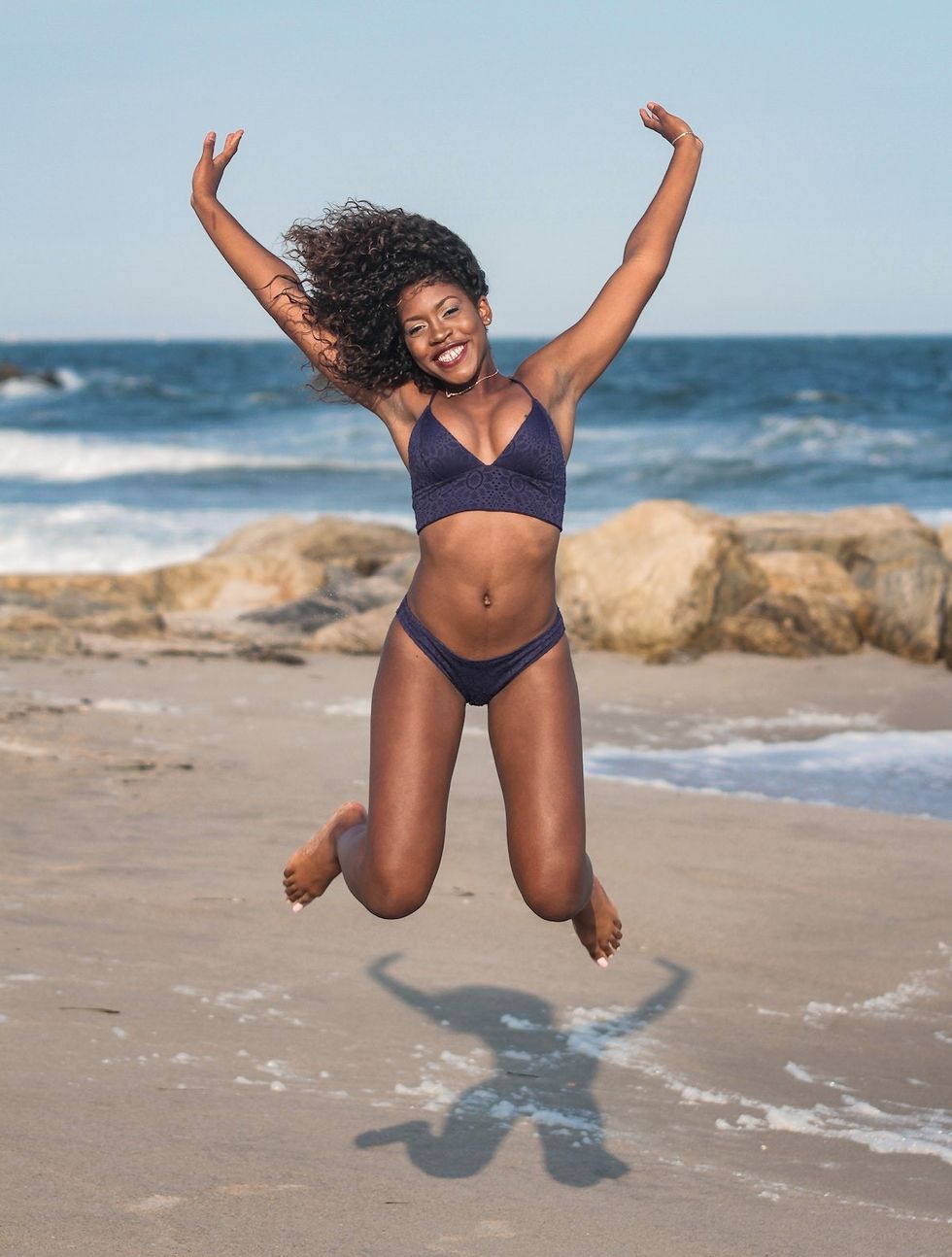 woman on the beach jumping for joy in the air
