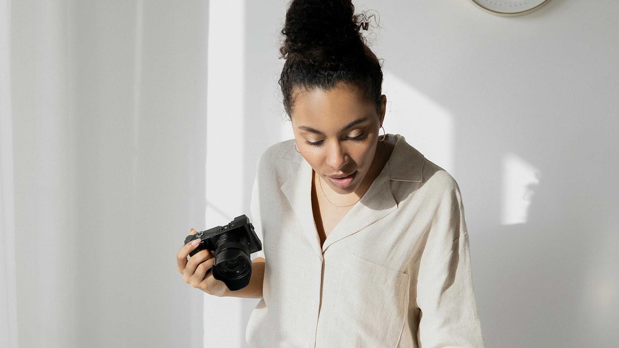 Woman photographing a cake on a table with color palettes and a wall clock.