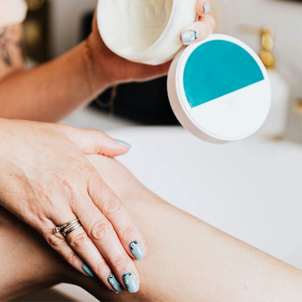 woman putting lotion on her legs