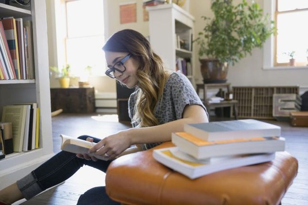 Woman reading books on living room floor