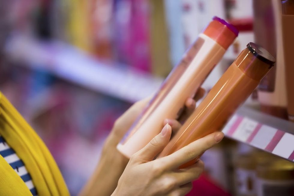 Woman reading shampoo bottles, comparing labels.